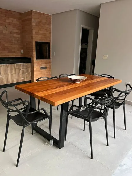 Mesa de jantar em madeira maciça instalada em área externa com piscina